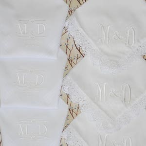 May include: Set of four white handkerchiefs with embroidered initials "M&D" and the text "Forever" in a simple font. Two handkerchiefs have a white lace trim around the edges.
