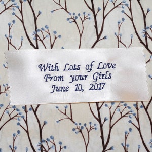 Può includere: Nastro di raso bianco con testo ricamato in blu che recita "With Lots of Love From your Girls June 10, 2017".