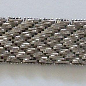 May include: A silver metal bracelet with a woven chain link design.