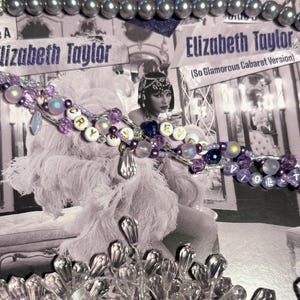 Puede incluir: Un collar de cuentas con cuentas moradas, blancas e iridiscentes que deletrean "CRY" y "VIOLET" se muestra sobre una imagen en blanco y negro de Elizabeth Taylor. La imagen es de una portada de &aacute;lbum. Tambi&eacute;n se ve un collar de perlas y detalles de cristal.