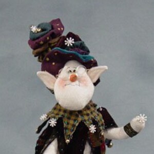 May include: A whimsical felt elf doll with a purple, green, and blue hat, wearing a black and green jester costume with white snowflakes and bells. The elf has a white face with a red nose and is holding a white snowflake in its hand.