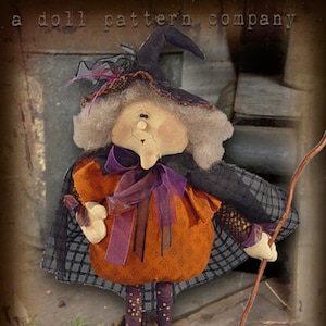 Peut inclure: Une poupée de sorcière faite à la main avec un chapeau noir, un ruban violet et une robe orange. La poupée tient un balai et se tient sur un tas de feuilles. La poupée est étiquetée "Sparkles 'n Spirit".