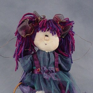 May include: A purple and teal fairy doll with a basket of berries and a star-shaped wand. The doll has a whimsical expression and is wearing a purple and teal dress with a tulle skirt.