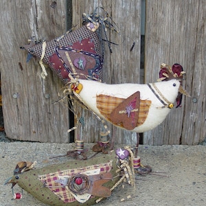 May include: Three handmade fabric chickens with different patterns and colors. The chickens are standing on a wooden surface.