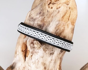 May include: A black leather bracelet with a silver braided design.
