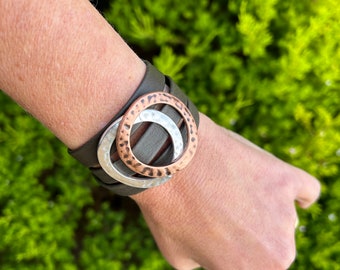 Triple reindeer leather bracelet with a magnetic clasp and two hammered large circles, copper and silver. It wraps around wrist three times.