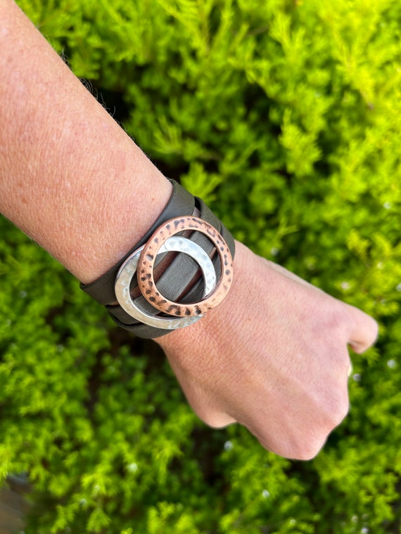 Triple reindeer leather bracelet with a magnetic clasp and two hammered large circles, copper and silver. It wraps around wrist three times.