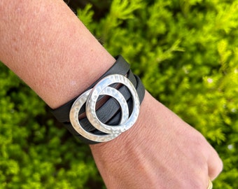 Nordic triple leather bracelet with a magnetic clasp and two hammered large silver circles. It wraps around wrist three times.