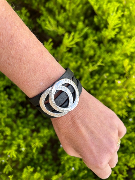 Nordic triple leather bracelet with a magnetic clasp and two hammered large silver circles. It wraps around wrist three times.