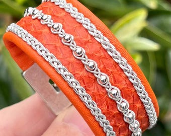 Sami inspired cuffs with reindeer and salmon leather combination. Made with three braids of pewter and sterling silver beads.