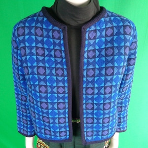 Może przedstawiać: Niebieski i fioletowy kardigan z geometrycznym wzorem i granatową lamówką. Kardigan ma długie rękawy i dekolt w kształcie litery V.