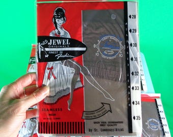 Puede incluir: Un paquete de medias de malla sin costuras Jewel Originals. El paquete presenta un dibujo de una mujer con un vestido y medias. El paquete también incluye el texto "Jewel Originals Finest in Fashion" y "Seamless Mesh".