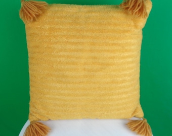 May include: A yellow throw pillow with a textured fabric and tassels on each corner.