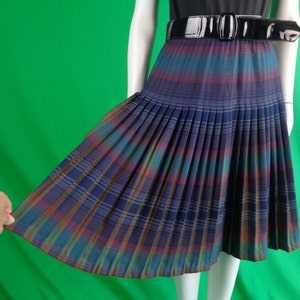 May include: A pleated midi skirt with a plaid pattern in shades of blue, green, red, and brown. The skirt has a black belt.