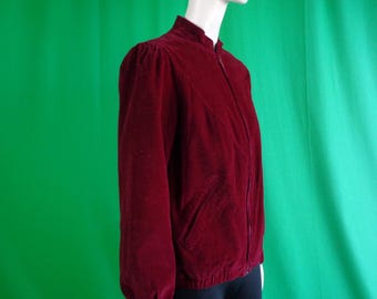 Puede incluir: Una chaqueta de pana color burdeos con cierre de cremallera y cuello alto.