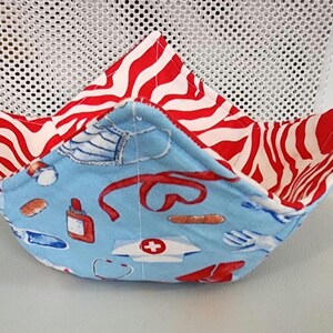 May include: A blue and white fabric bowl with a red and white zebra print lining. The bowl features a variety of medical-themed illustrations, including a stethoscope, bandages, and a pill bottle.