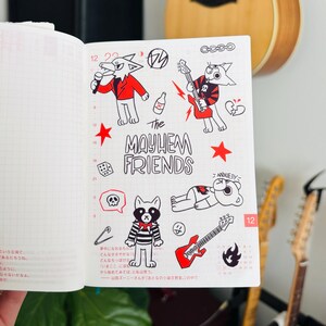 May include: A white notebook page with black and red drawings of cartoon animals. The animals are playing music and have a band name that says "The Mayhem Friends".