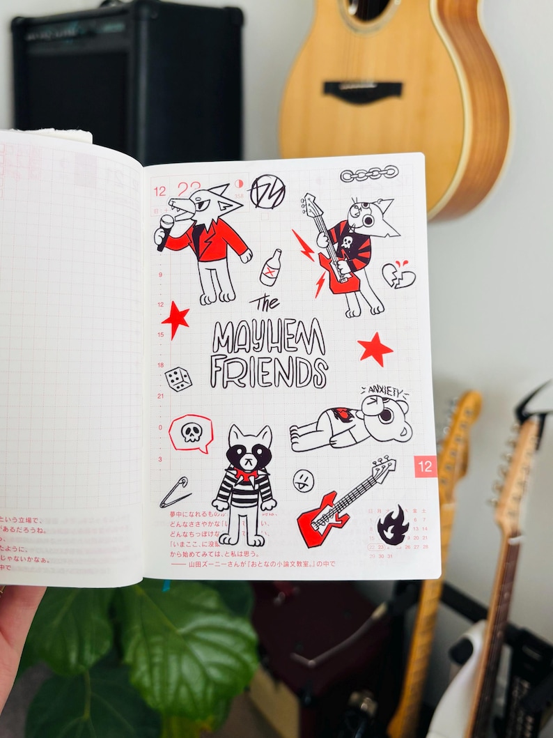 May include: A white notebook page with black and red drawings of cartoon animals. The animals are playing music and have a band name that says "The Mayhem Friends".