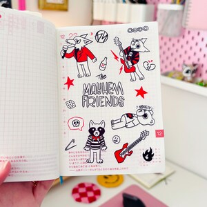 May include: A page from a planner with black and white illustrations of cartoon animals. The animals are playing music and have a punk rock aesthetic. The text "The Mayhem Friends" is written in black and white.