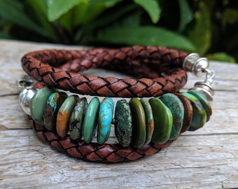 May include: A brown leather bracelet with a braided design and a row of turquoise stones. The bracelet has a silver clasp.