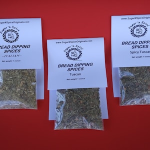 May include: Three white bags of bread dipping spices, each with a different flavor: Italian, Tuscan, and Spicy Tuscan. Each bag contains 1 ounce of spices.