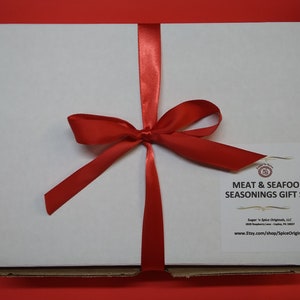 May include: A white gift box tied with a red ribbon bow. The box is labeled "Meat & Seafood Seasonings Gift Set" with the company name "Sugar 'n Spice Originals, LLC" and website address "www.etsy.com/shop/SpiceOriginals".