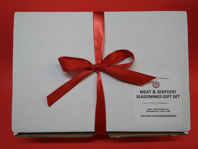 May include: A white gift box tied with a red ribbon bow. The box is labeled "Meat & Seafood Seasonings Gift Set" with the company name "Sugar 'n Spice Originals, LLC" and website address "www.etsy.com/shop/SpiceOriginals".