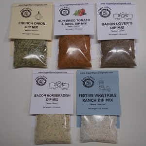 May include: Six small bags of dip mix with labels. The labels are white with black text and a cartoon image. The dip mixes are: French Onion Dip Mix, Sun-Dried Tomato & Basil Dip Mix, Bacon Lover's Dip Mix, Bacon Horseradish Dip Mix, Festive Vegetable Ranch Dip Mix.