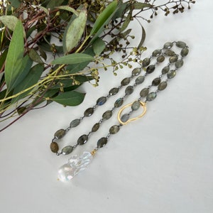 May include: A long silver chain necklace with oval-shaped green labradorite stones and a gold pendant with a pearl drop.