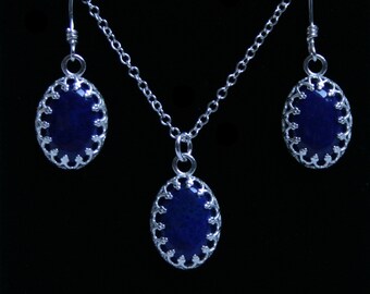 May include: A silver necklace and earrings set with dark blue oval stones set in ornate silver frames.