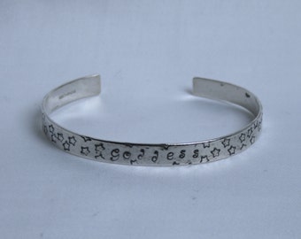 Traditionally hand made cuff bracelet. 'Goddess'  Hammered finish with words and stars. Fully UK Hallmarked Silver.