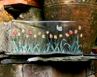 Tulip Garden.  A row of tulips with a flitting butterfly. A hand painted, fused glass free standing 'wave'  Approx. 10 x 25 cm (4 x 10")