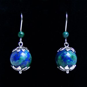 May include: A pair of silver earrings with blue and green gemstone beads. The beads are round and have a textured surface. The earrings are dangle style with a small bead at the top of the dangle.