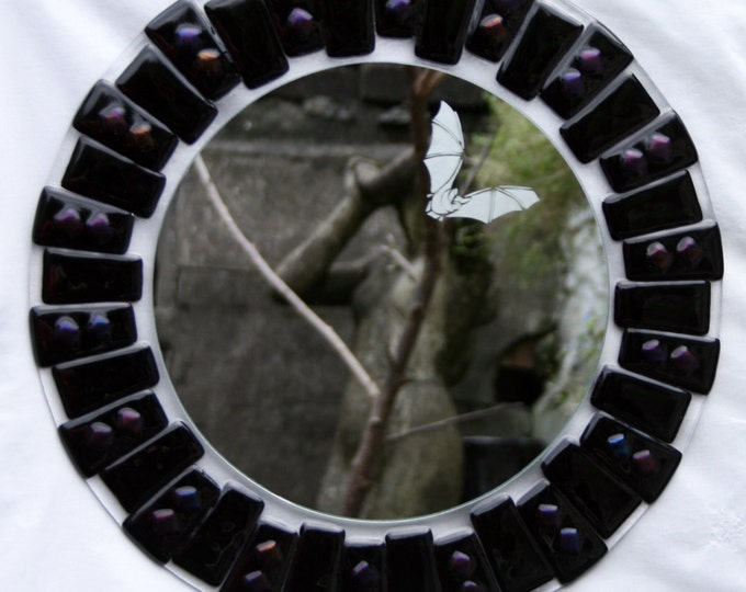 Night Flight ~ A Fused glass circular mirror in glossy black with shimmering highlights of purples and blue, etched with a flying bat