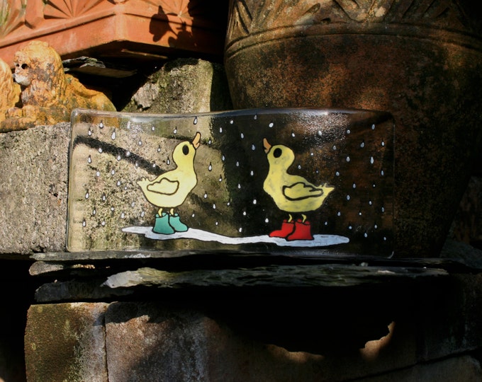 Duckling Duo. A pair of cute ducklings in wellies in the rain. A hand painted, fused glass free standing 'wave'  Approx 10 x 25 cm (4 x 10")