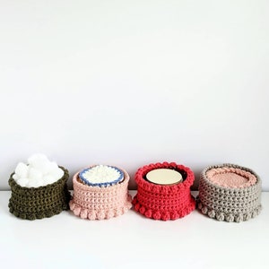 Puede incluir: Cuatro cestas de crochet en diferentes colores y estilos. Las cestas est&aacute;n alineadas en una fila sobre una superficie blanca. Las cestas est&aacute;n hechas con una variedad de puntadas y texturas.