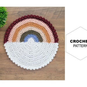 Puede incluir: Una alfombra de crochet arcoíris colorida con un diseño de nube blanca. El arcoíris está hecho de hilo rojo, naranja, amarillo, verde, azul y morado. La alfombra es perfecta para agregar un toque de fantasía a cualquier habitación.