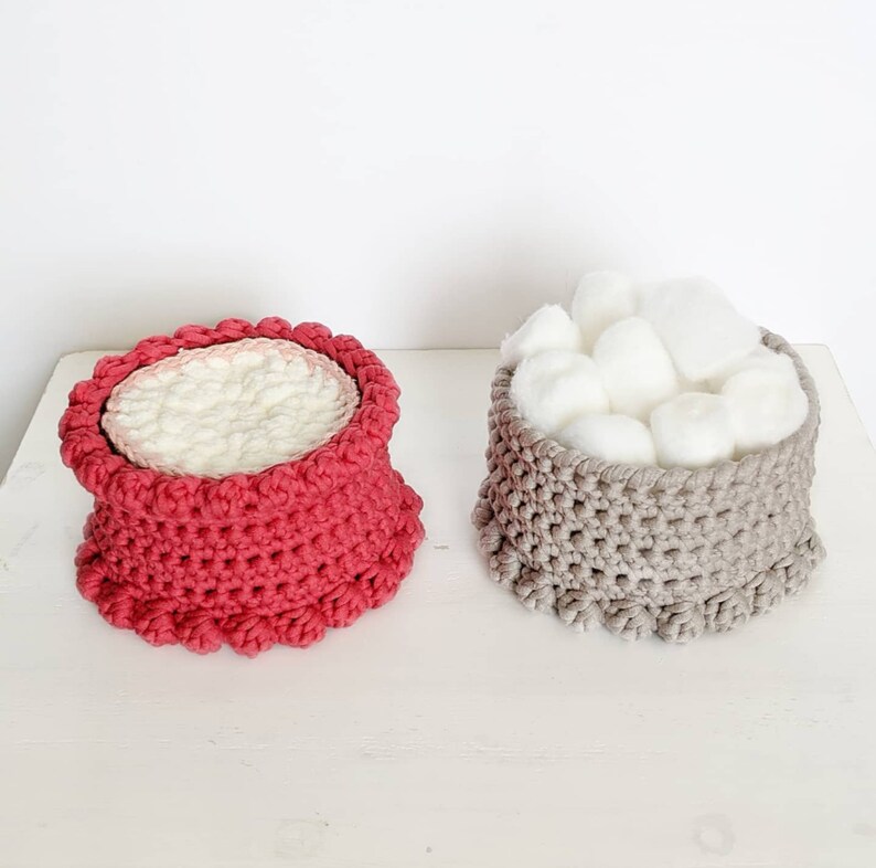 Puede incluir: Dos cestas de crochet, una roja y otra gris, con un relleno de bolas de algod&oacute;n blancas en la cesta gris.