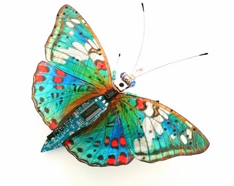 May include: A colorful butterfly with a circuit board embedded in its body. The butterfly's wings are a mix of blue, green, red, and white.