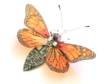 May include: A butterfly with orange and brown wings is made from a circuit board. The butterfly's body is made from small electronic components.