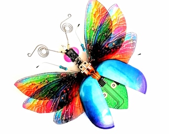 May include: A colorful butterfly sculpture made from recycled materials, including a circuit board, with iridescent wings and a blue body.