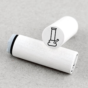 May include: Two white wooden stamps with a black outline of a bong on the stamp face. One stamp is upright, and the other is lying down. The stamp's handle is white with a black and gray ink pad.