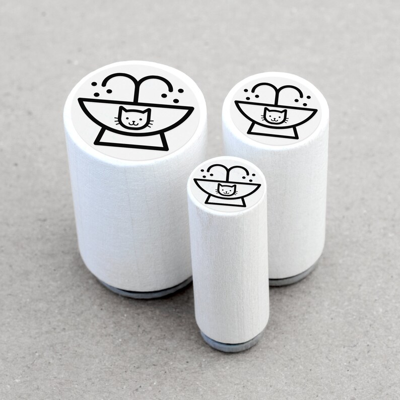 May include: Three white rubber stamps with a black outline of a cat in a bath with water spraying from the tap. The stamps are different sizes.