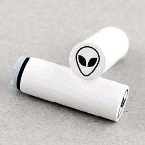 Peut inclure: Deux tampons en bois blanc avec des tampons d'encre noirs. Le tampon supérieur présente un motif de visage extraterrestre. Le tampon inférieur présente un motif de visage extraterrestre partiel.