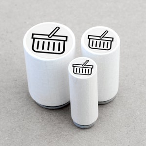 DE: Drei runde Ministempel mit dem Motiv 'Einkaufskorb' im direkten Größenvergleich: Ø 1,1 cm, Ø 1,5 cm und Ø 2 cm. Die kleinen Motivstempel bestehen aus weiß lackiertem Ahornholz mit schwarzer Zwischenlage und transparentem Motivaufkleber.
EN: Three round mini rubber stamps with the 'Shopping Basket' design in a direct size comparison: Ø 1.1 cm, Ø 1.5 cm and Ø 2 cm. These small rubber stamps are made of white lacquered maple wood with a black cushioning layer and a transparent label.