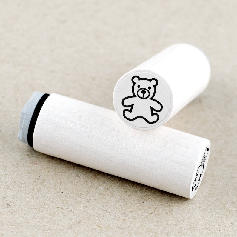 DE: Runder Ministempel mit Motiv 'Teddybär'. Das Stempelgummi ist an ein weiß lackiertes Ahornholz montiert. Das Motiv ist als transparenter Aufkleber auf der Oberseite sichtbar. Der Stempel ist ideal für Bullet Journals, Kalender oder kreative Papiergestaltung.
EN: Round mini rubber stamp with the 'Teddy Bear' design. The rubber stamp is mounted on white lacquered maple wood, with a transparent label on top showing the motif. Perfect for bullet journals, planners or creative paper crafting.