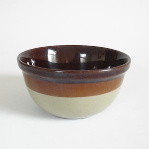 May include: A brown and beige ceramic mixing bowl with a glazed finish.