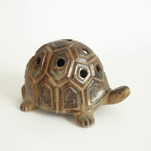 May include: A white ceramic mug with a black handle and the text "But First, Coffee" in a black, handwritten-style font. The mug is on a white surface.