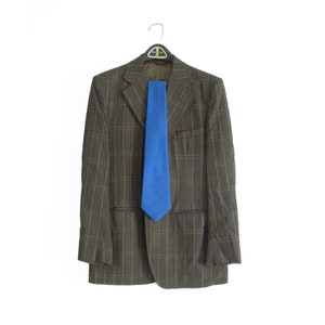 May include: A brown plaid blazer with a blue tie hanging from the collar. The blazer is on a hanger against a white background.