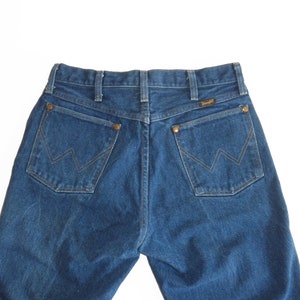 May include: A pair of blue denim jeans with a classic five-pocket design. The back pockets feature a stitched 'W' logo.